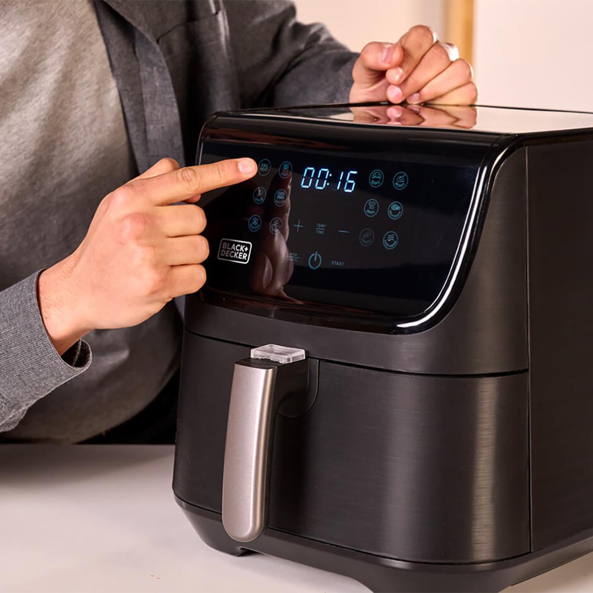 Person som justerar inställningarna på en svart Airfryer Black+Decker 1800W 5,5L