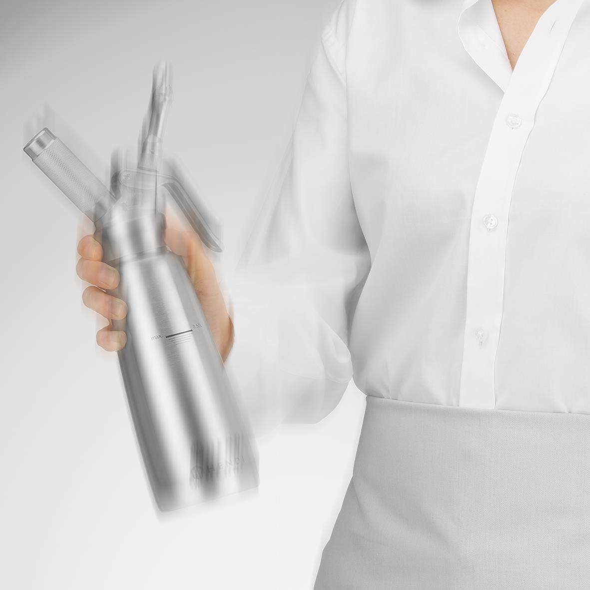 Person i vit skjorta håller en silverfärgad flaska med en spruta eller pipett