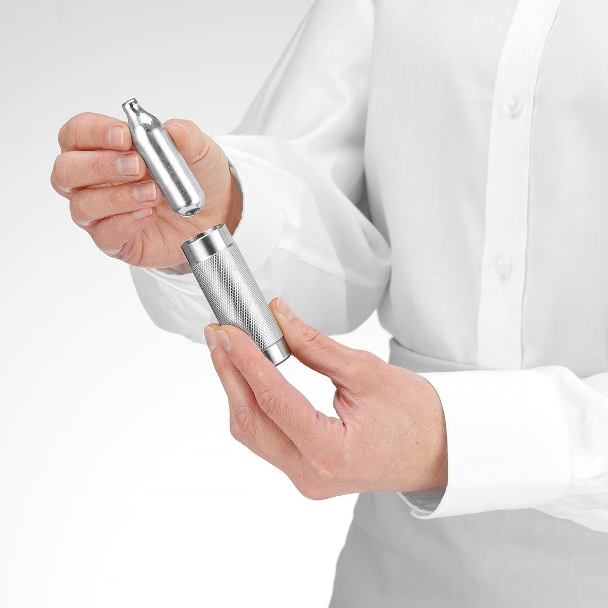 Person håller en elektrisk nagelfil eller buffare i handen, klädd i vit skjorta