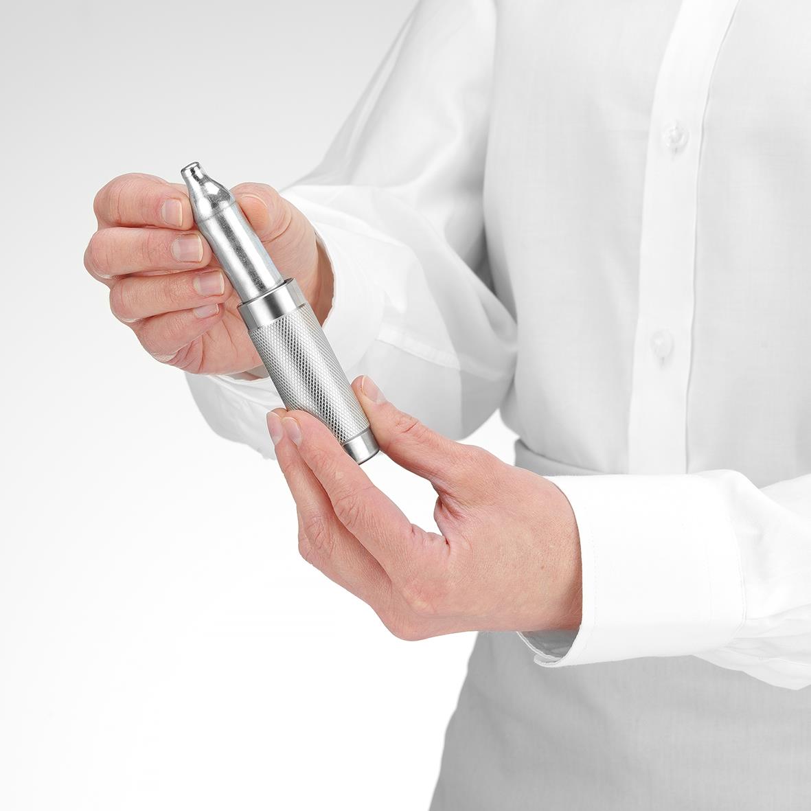 Person håller en medicinsk eller skönhetsrelaterad apparat i handen