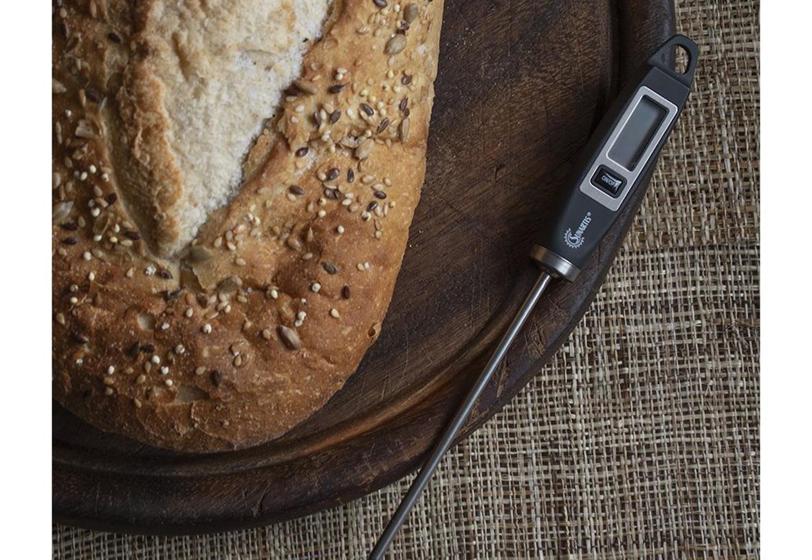 Digitalt termometer Sunaris svart med 200mm längd, placerad på ett träbord bredvid ett bröd