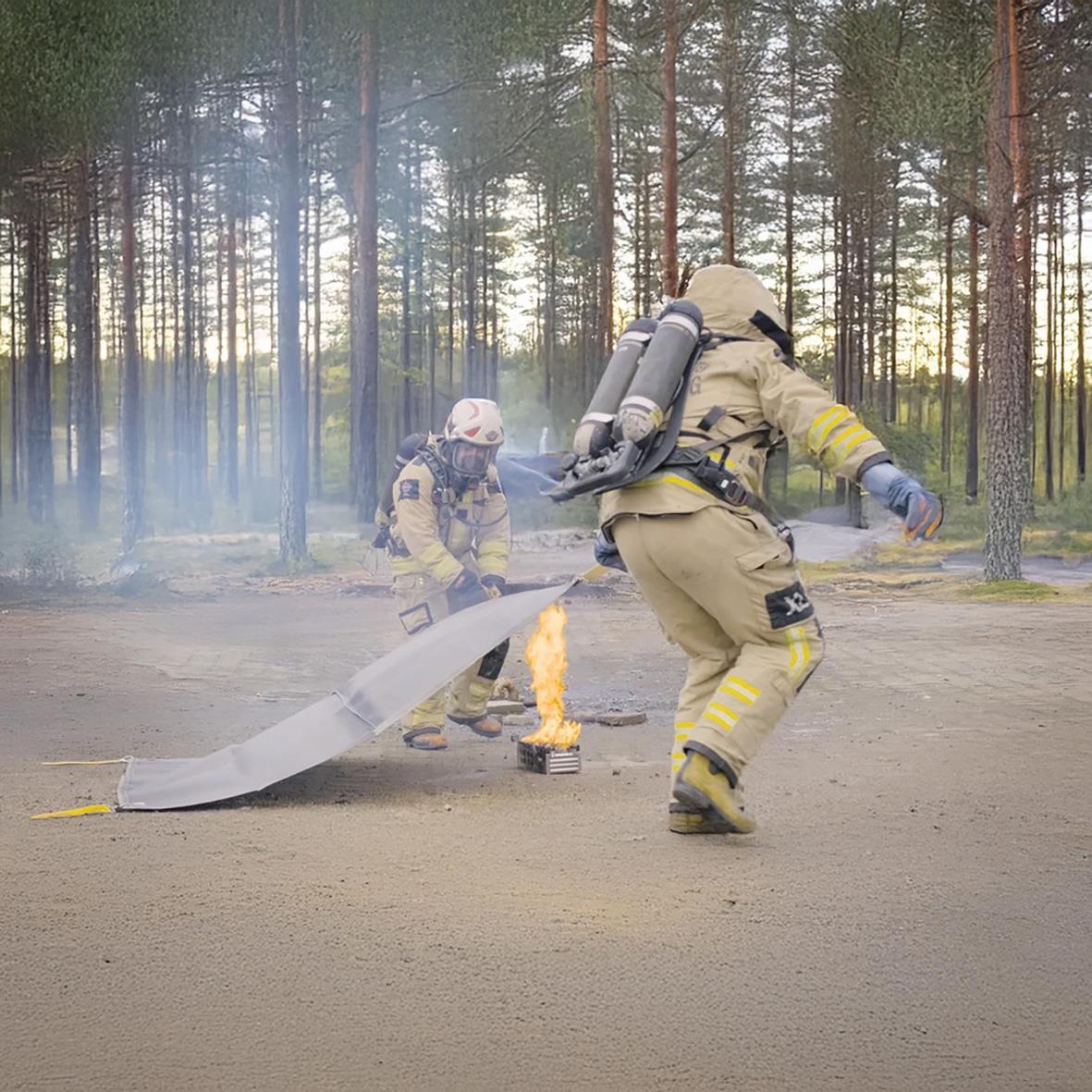 Brandmän använder brandfilt i skogsområde för att släcka liten brand