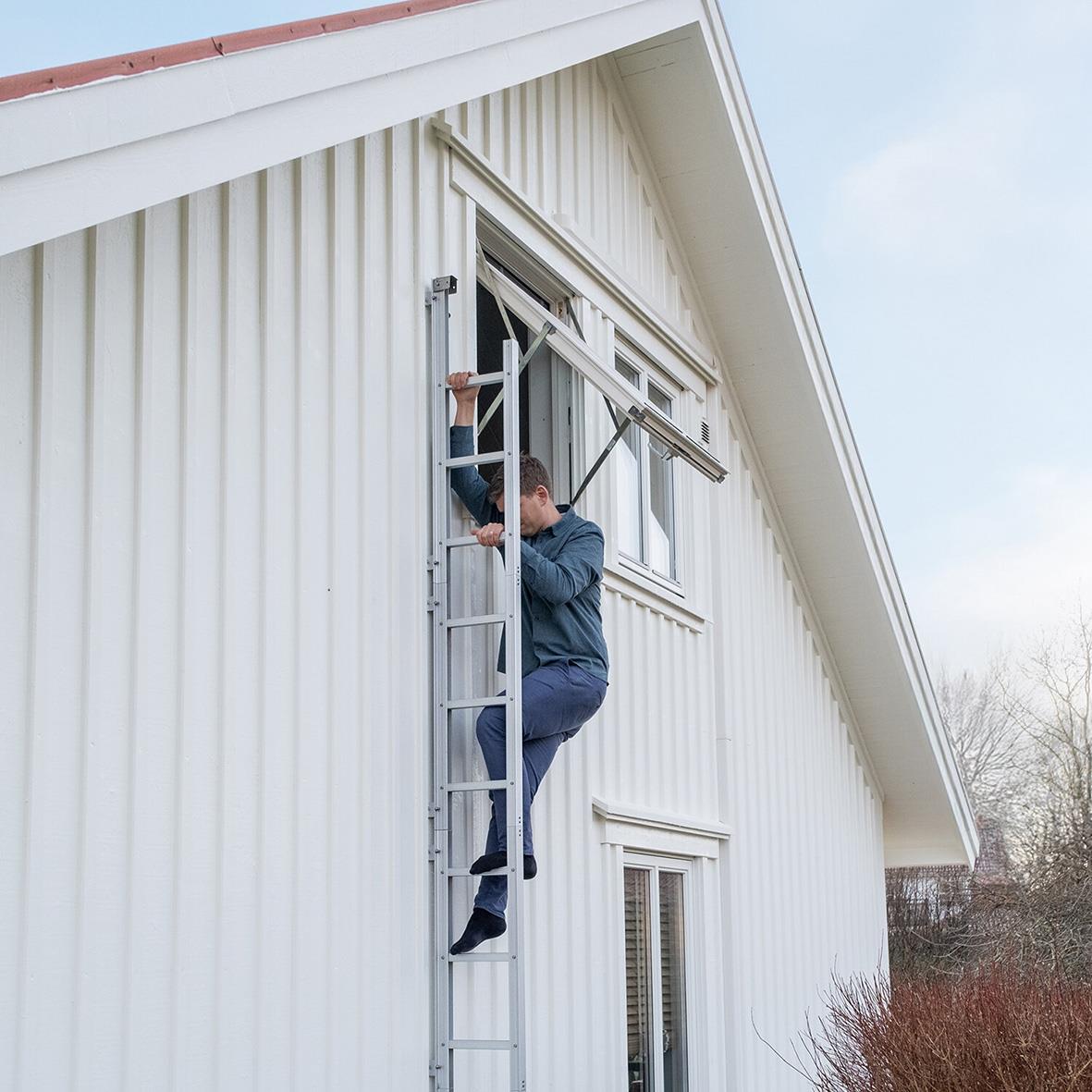 Person som använder en utrymningsstege på utsidan av ett vitt hus
