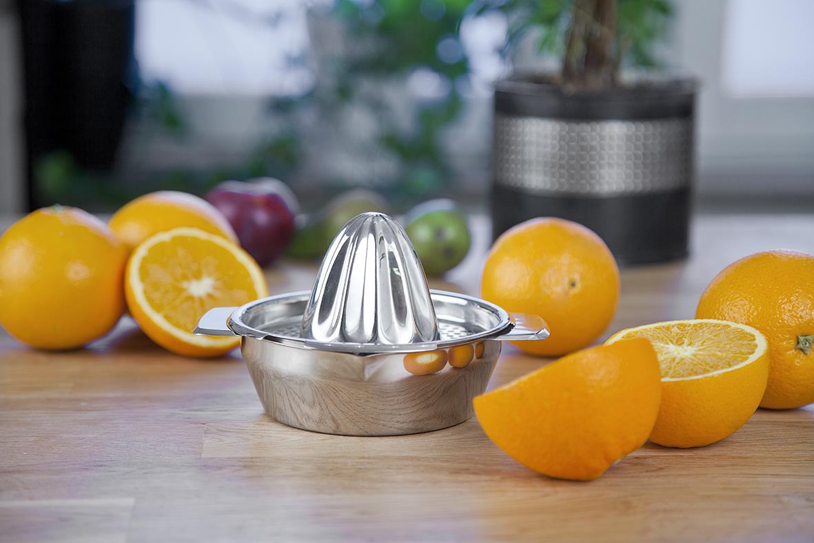 Rostfri citronpress med hela och halva citroner på träbänk