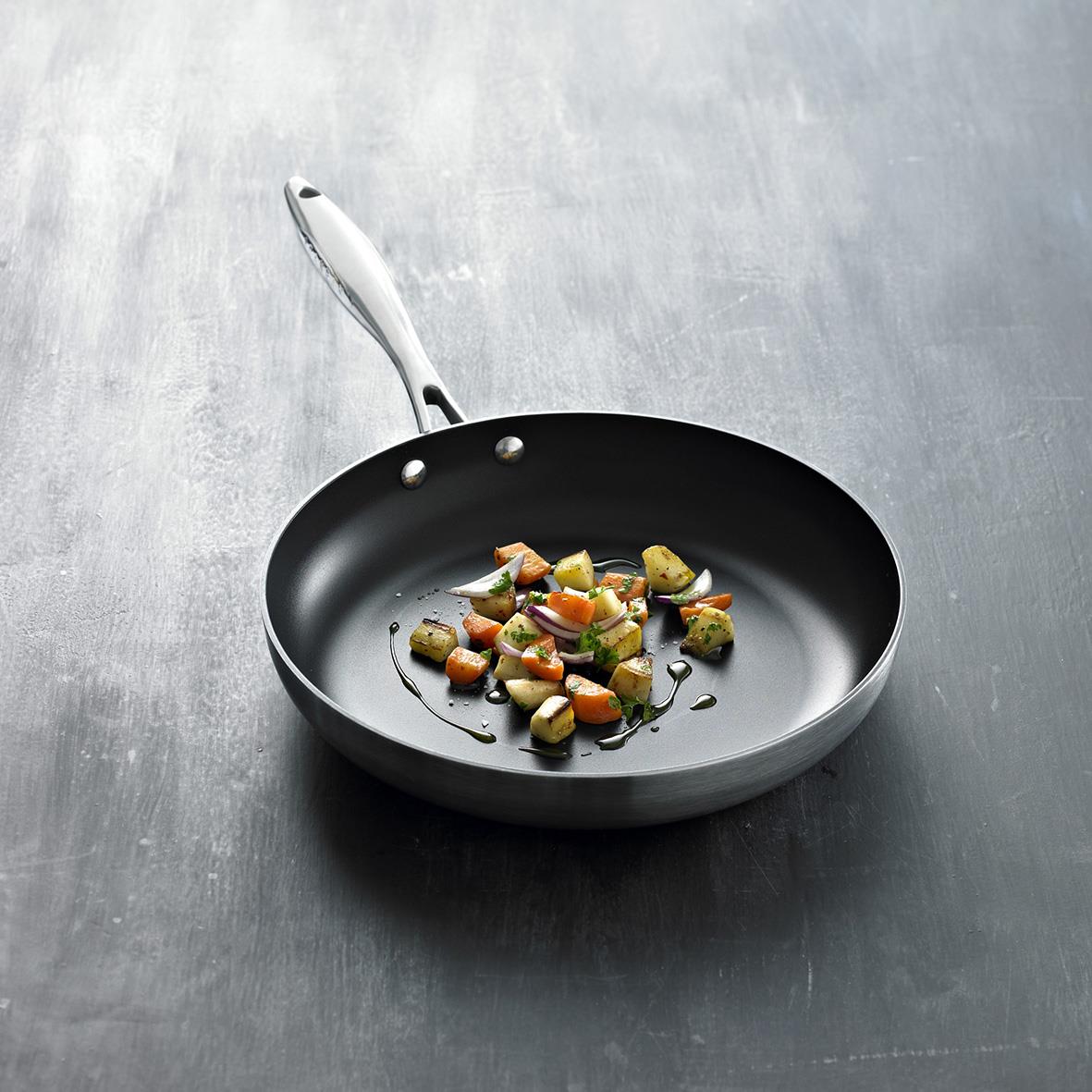 Stekpanna Scanpan CTX Ø32cm med stekt grönsaker på en grå bakgrund