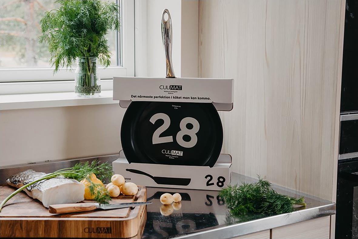 Stekpanna Culimat med diameter 28 cm, placerad på en bokstapel i ett kök med fönster och gröna växter i bakgrunden