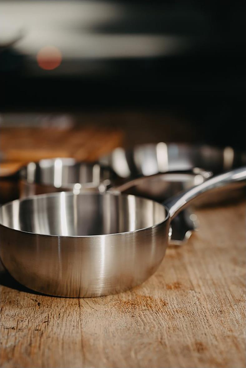 Sauteuse panna i rostfritt stål med träskiva på en köksbänk