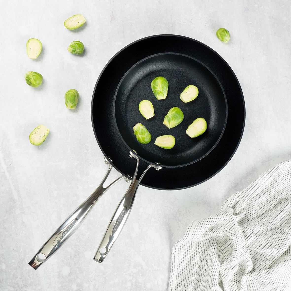 Stekpanneset Scanpan HaptIQ Ø28+20cm med bruna bruksrester och gröna brusselklot på en ljus bakgrund