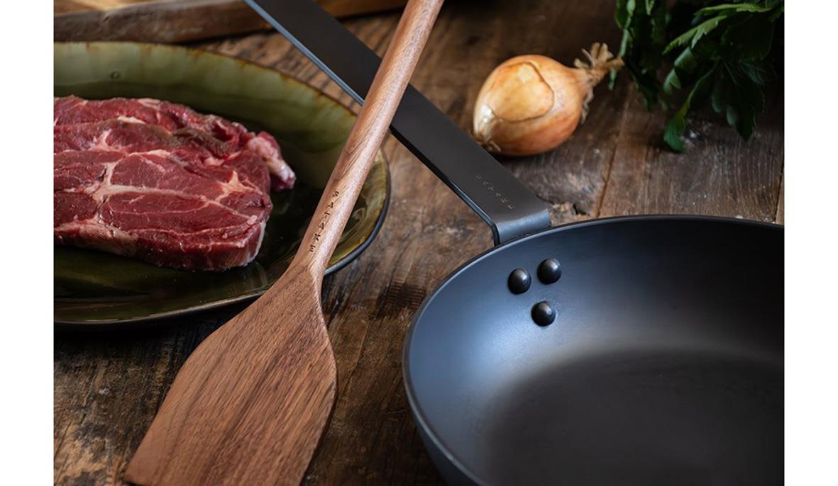 Stekpanna Satake Kolstål 3mm Ø28cm med träspade och kött på träskärbräda