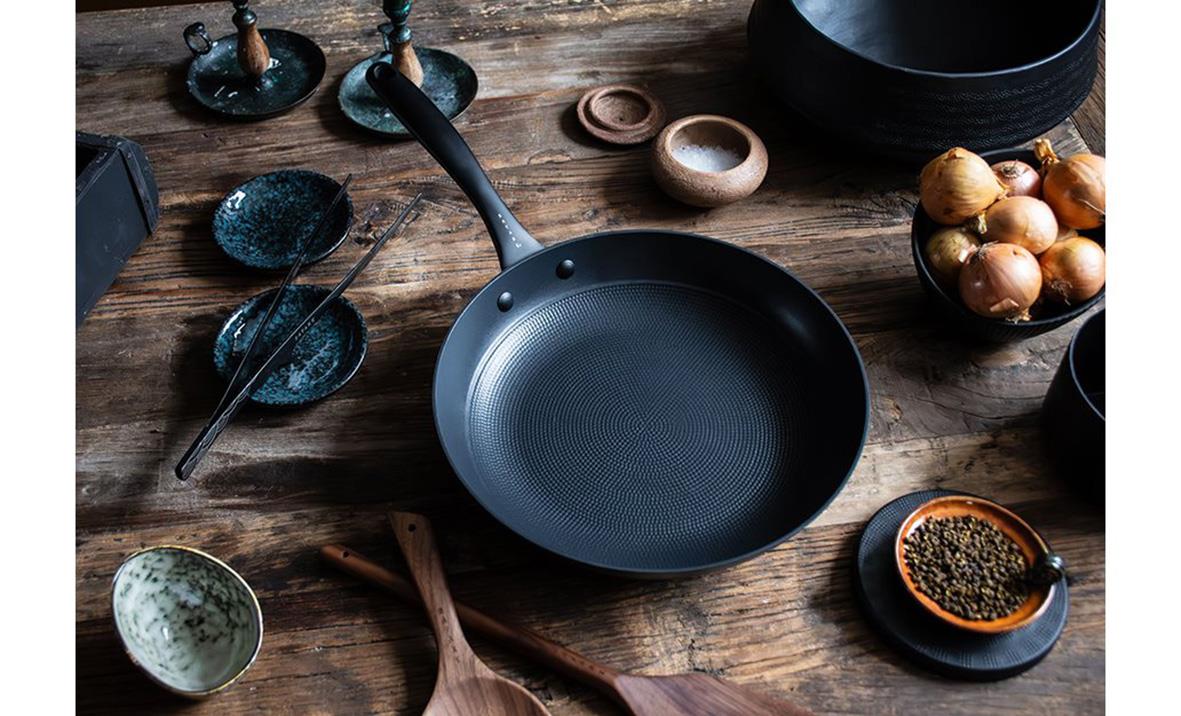 Satake lättviktsgjutjärn stekpanna Ø28cm på träbord med olika köksredskap och kryddor