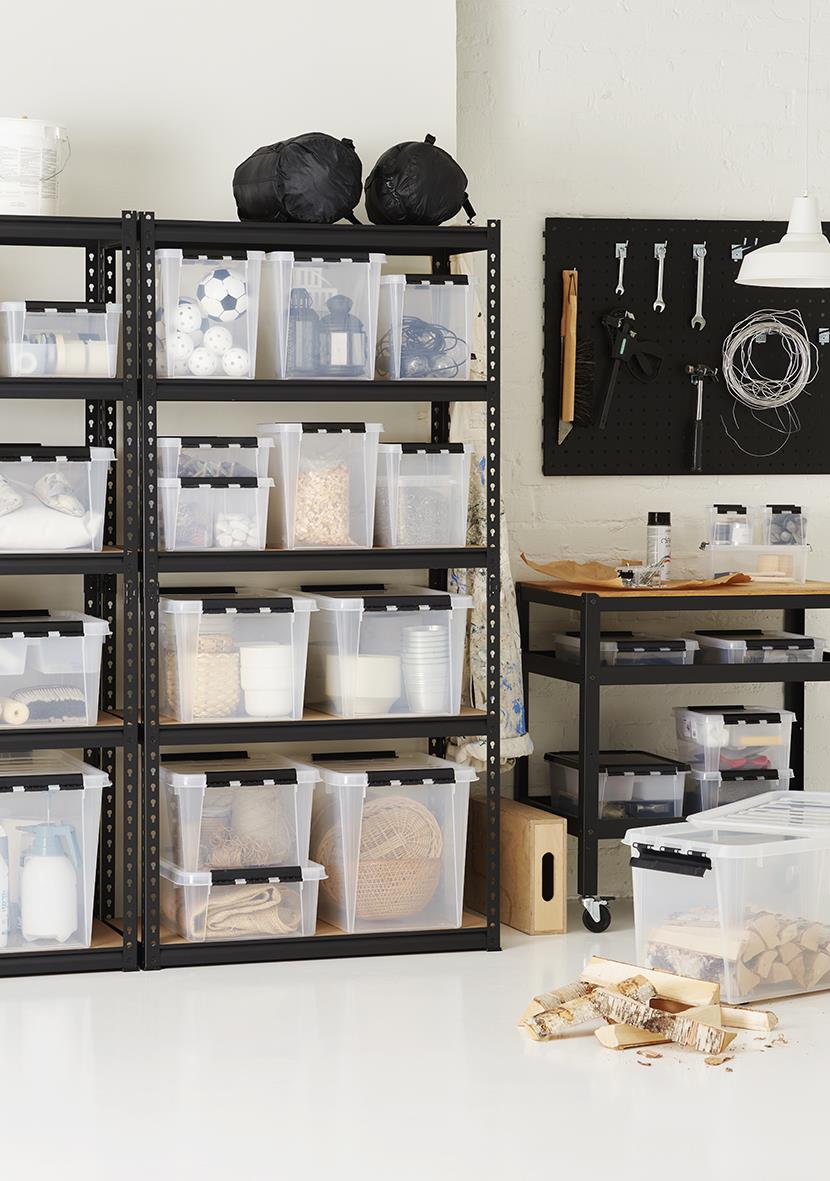 Förvaringslådor i transparent plast på svart metallhylla, organiserade med olika föremål i ett arbetsrum eller hobbyrum