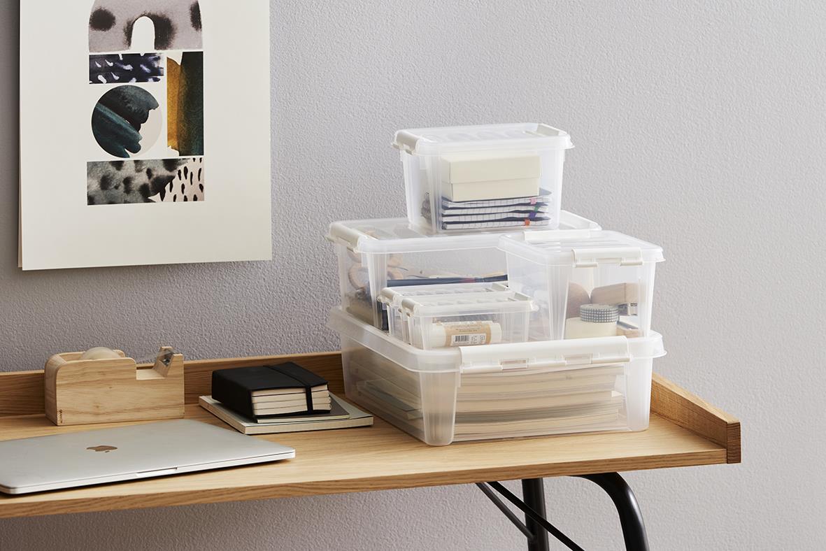 Förvaringslådor i plast staplade på ett skrivbord, används för organisering