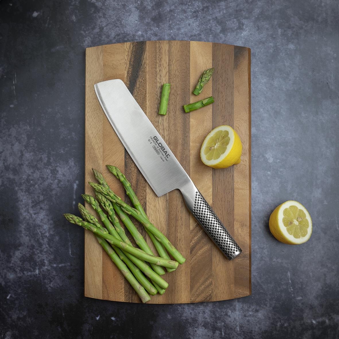 Grönsakshacka Global G-5 18cm kniv på träskärbräda med sparris och citron