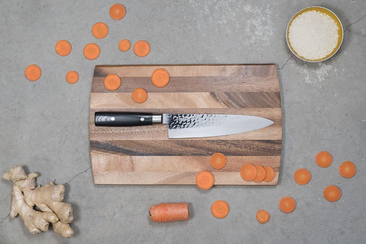 Kockkniv Yaxell Zen 20cm på skärbräda med morötter, ingefära och salt