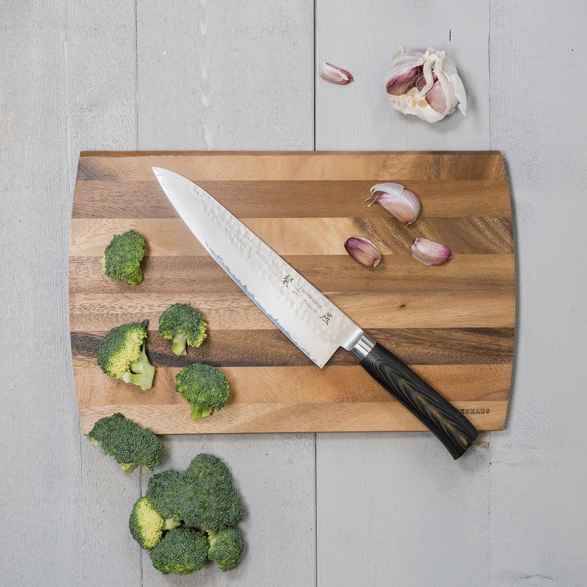 Kockkniv Tamahagane San Tsubame 21cm på träskärbräda med broccoli och vitlök
