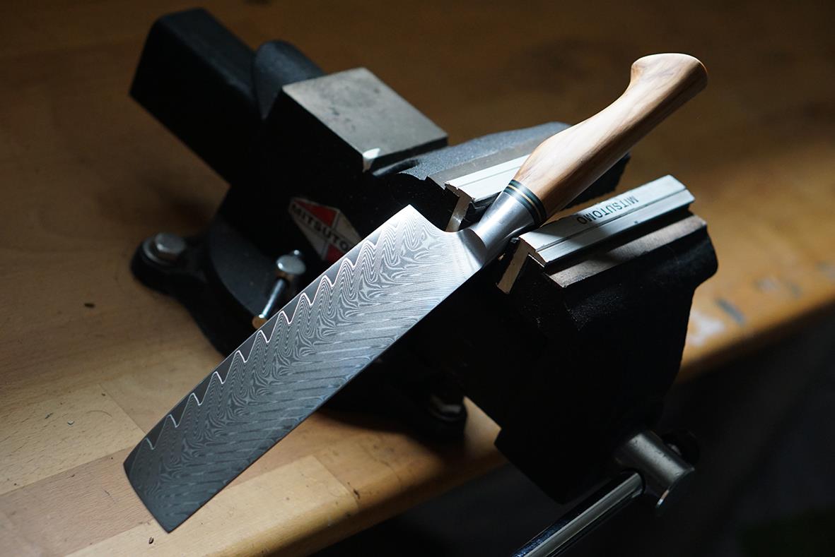 Nakirikniv Ryda Knives 18cm med trähandtag och tandad blad liggande på en arbetsbänk