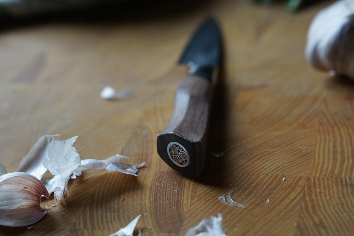 Skalkniv Ryda Knives A-30 9cm liggande på ett träbord med vitlök och skal