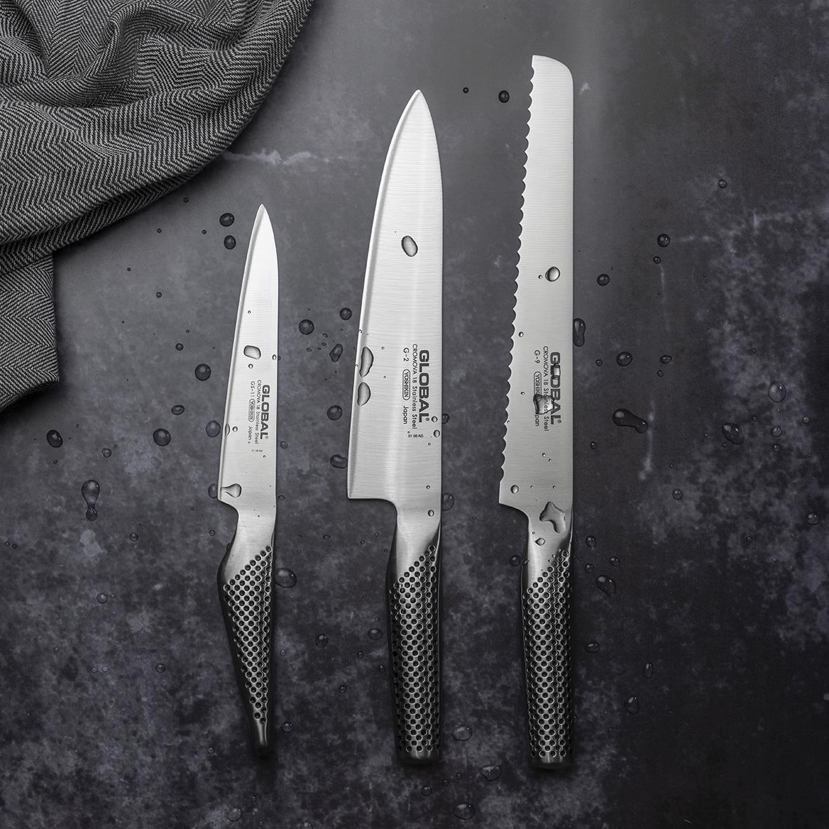 Knivset med tre olika storlekar av knivar på mörk bakgrund, inklusive en brödkniv, kockkniv och liten kniv