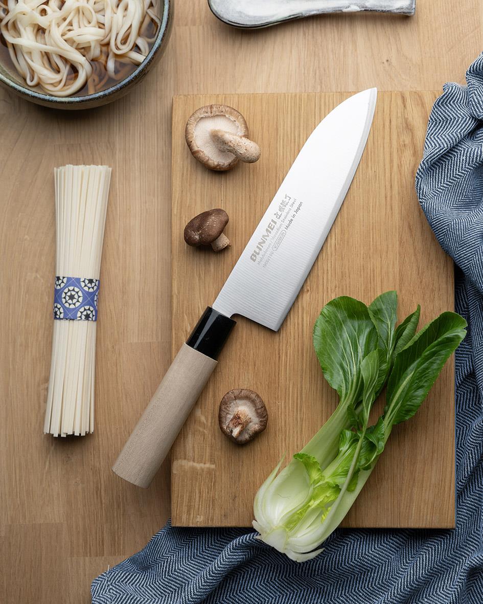 Santokukniv Bunmei 18cm på träskärbräda med svamp, pasta och grönsaker