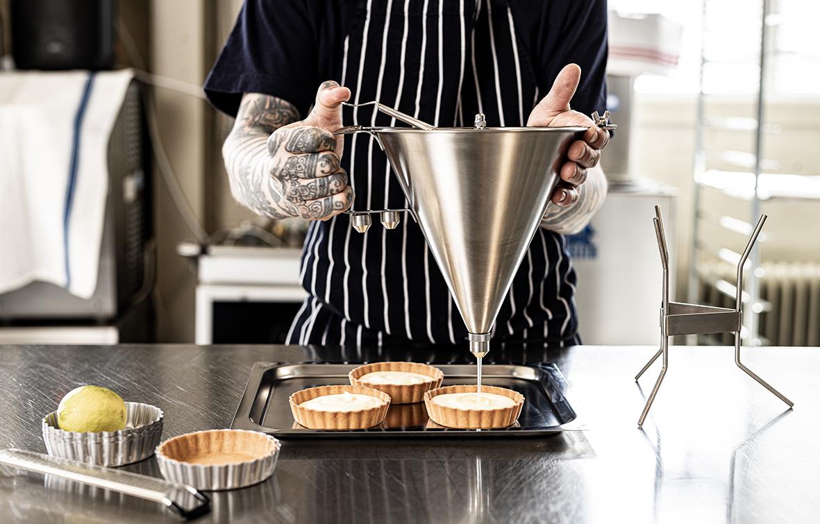 Person fyller sås i en 1,5L portioneringsbehållare i ett kök