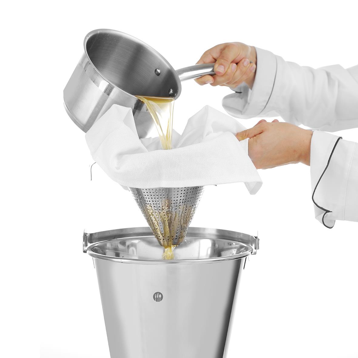 Person häller varm vätska genom en silduk i en metallhink