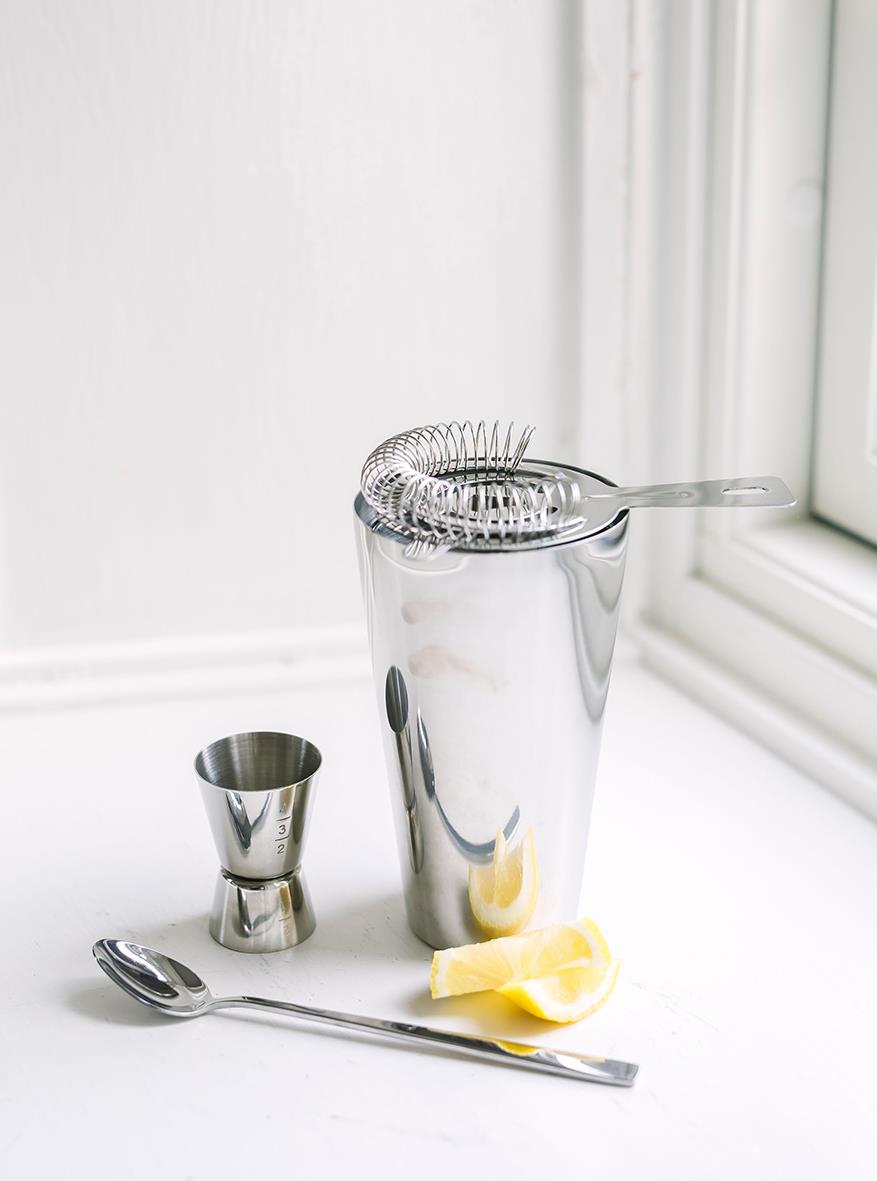 Sila och jigger för drinkar på ett vitt fönsterbräde, med citron och en sked