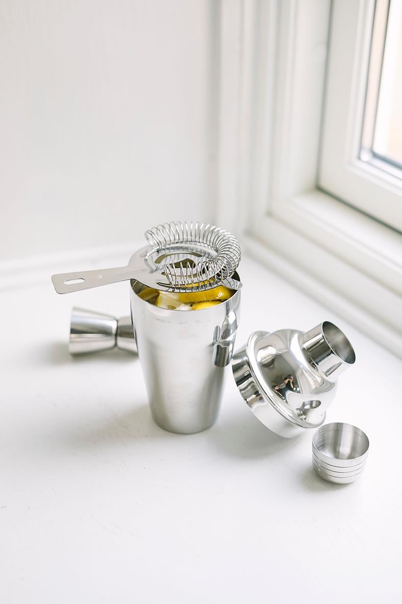 Stainless steel cocktail shaker med tillbehör på fönsterbräda