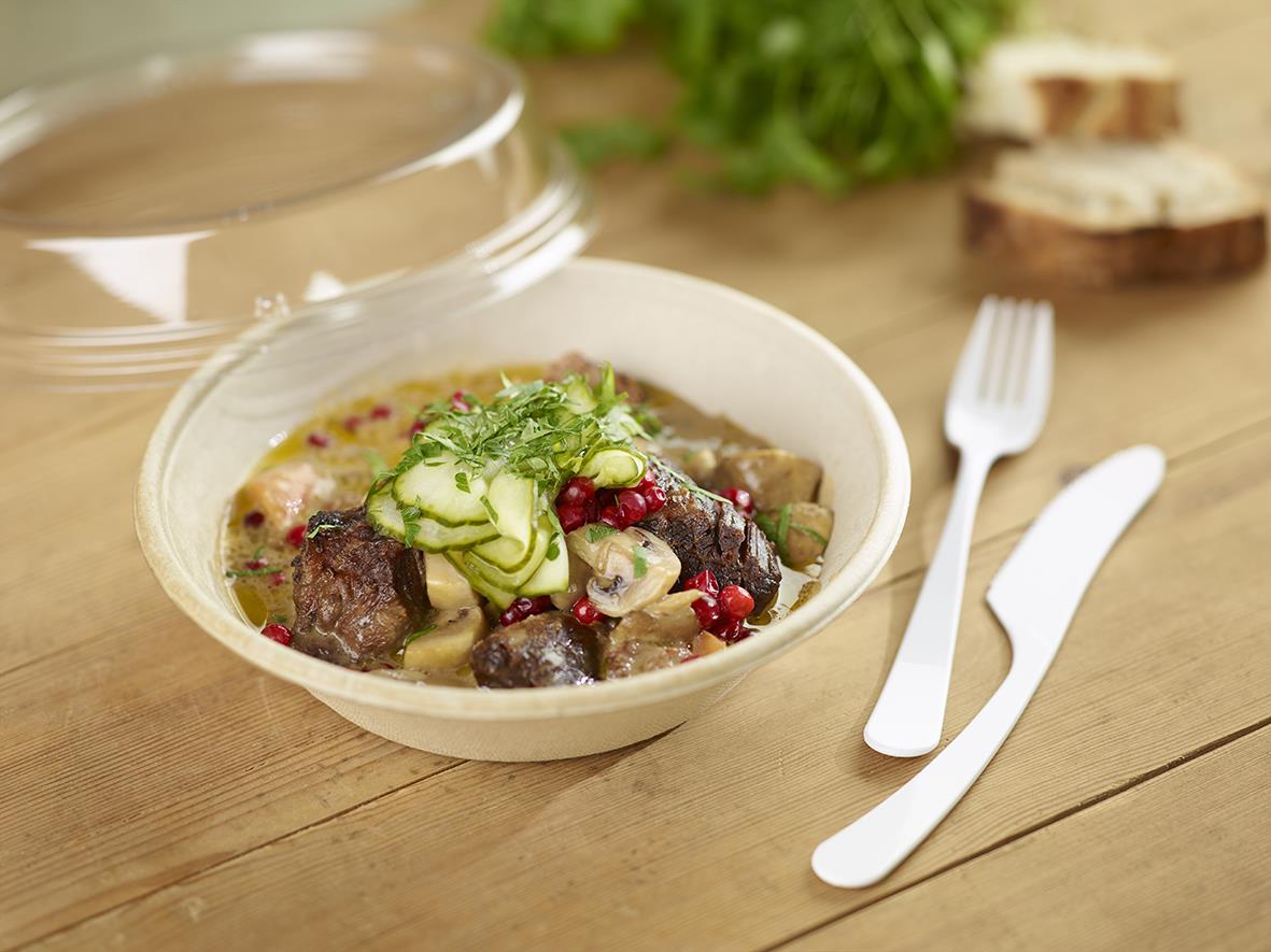Skål Duni Bagasse 800ml med köttgryta, gurka och bär på träbord med sked och kniv