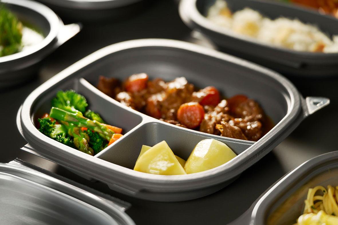 Grå plastlåda med tre fack fylld med mat, inklusive kött, broccoli och potatis