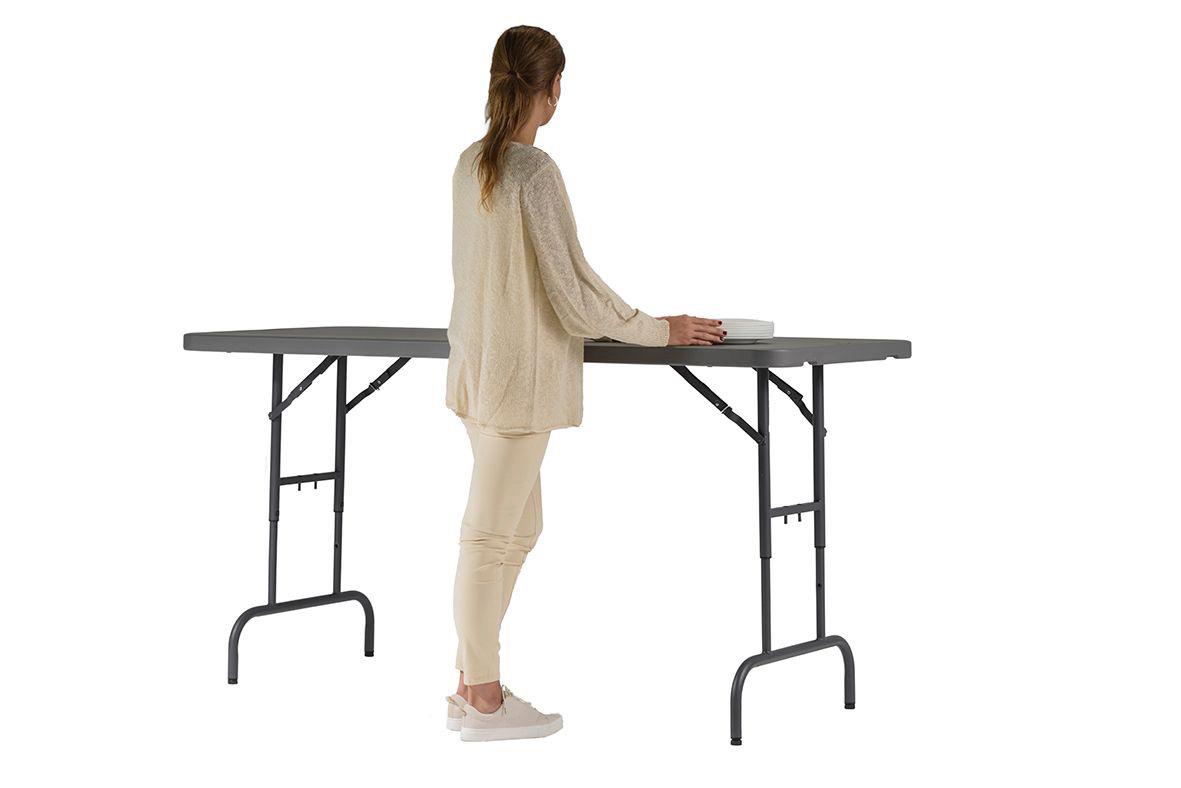 Person som står vid ett mörkgrått, fällbart arbetsbord med måtten 183x76x74,3cm