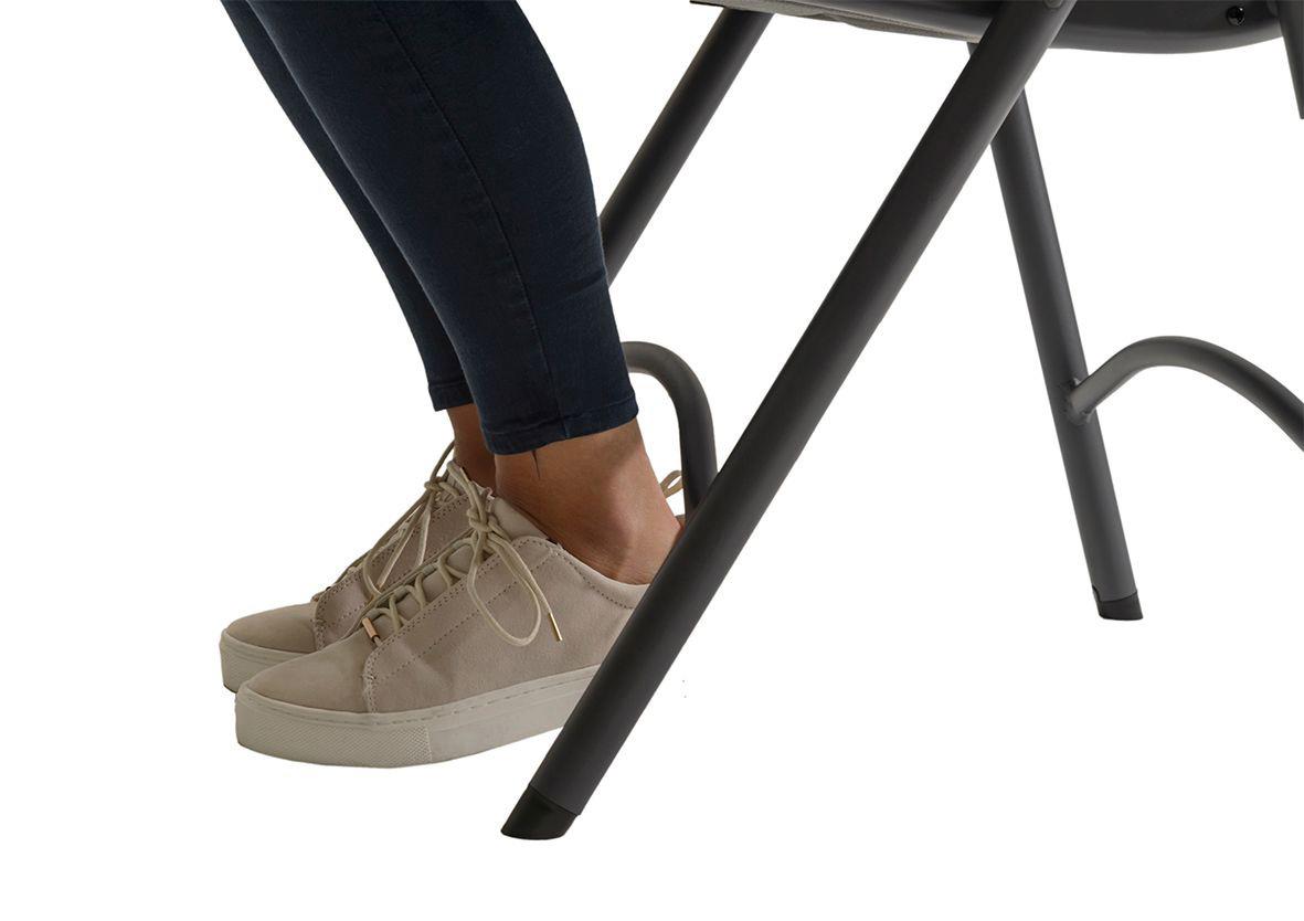 Fällbar stol med ljusgrå sits och svarta ben, person sitter med ljusfärgade sneakers