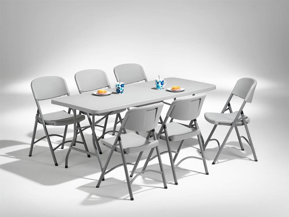 Fällbar stol i ljusgrå färg runt ett bord med tallrikar och glas