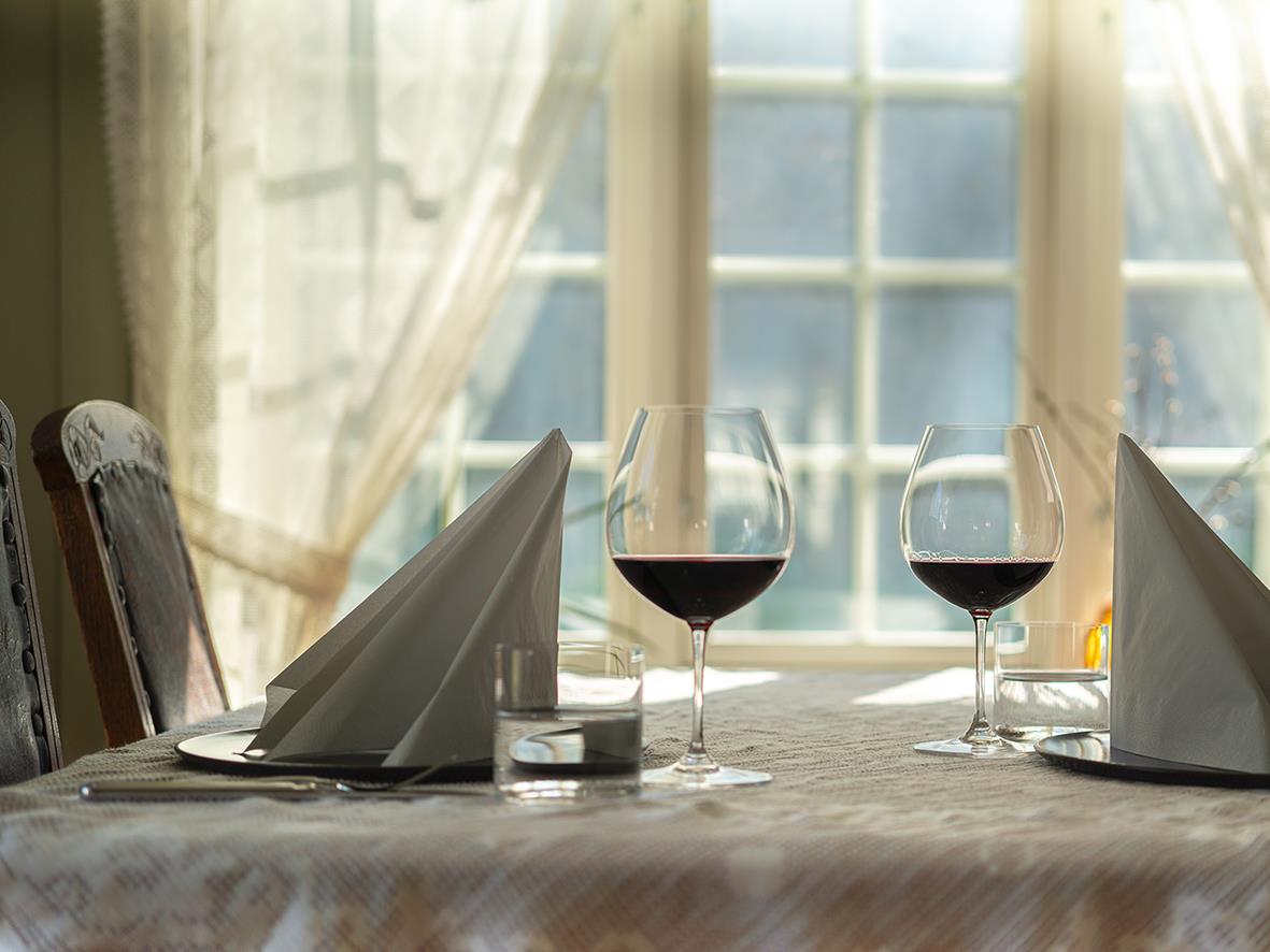 Vinglas Riedel Vinum Pinot Noir på ett dukat bord med två glas vin och servetter