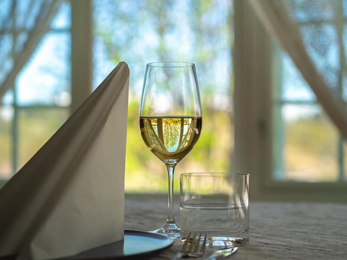 Vinglas Riedel Vinum Zinfandel/Riesling med guldfärgad dryck på ett bord med glas och servetter