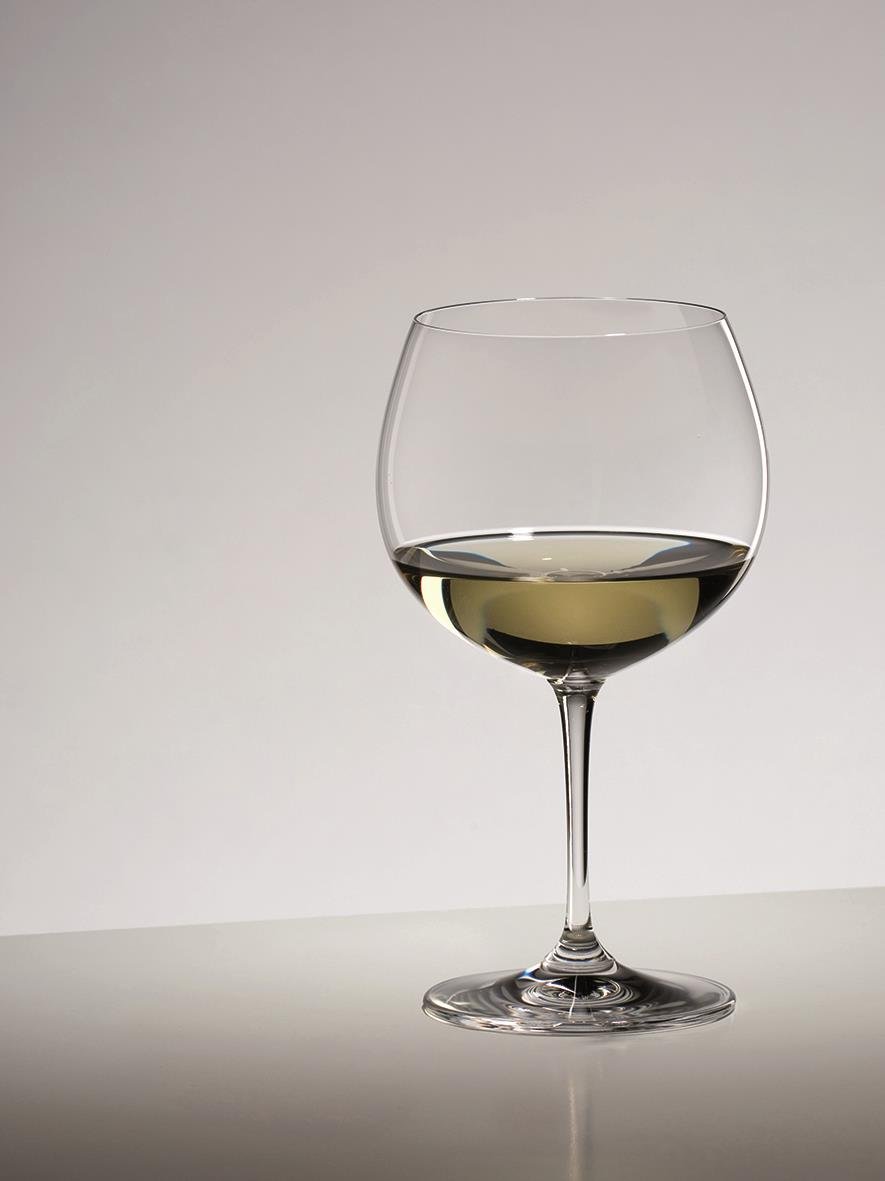 Vinglas Riedel Vinum Chardonnay med vitt vin på en neutral bakgrund