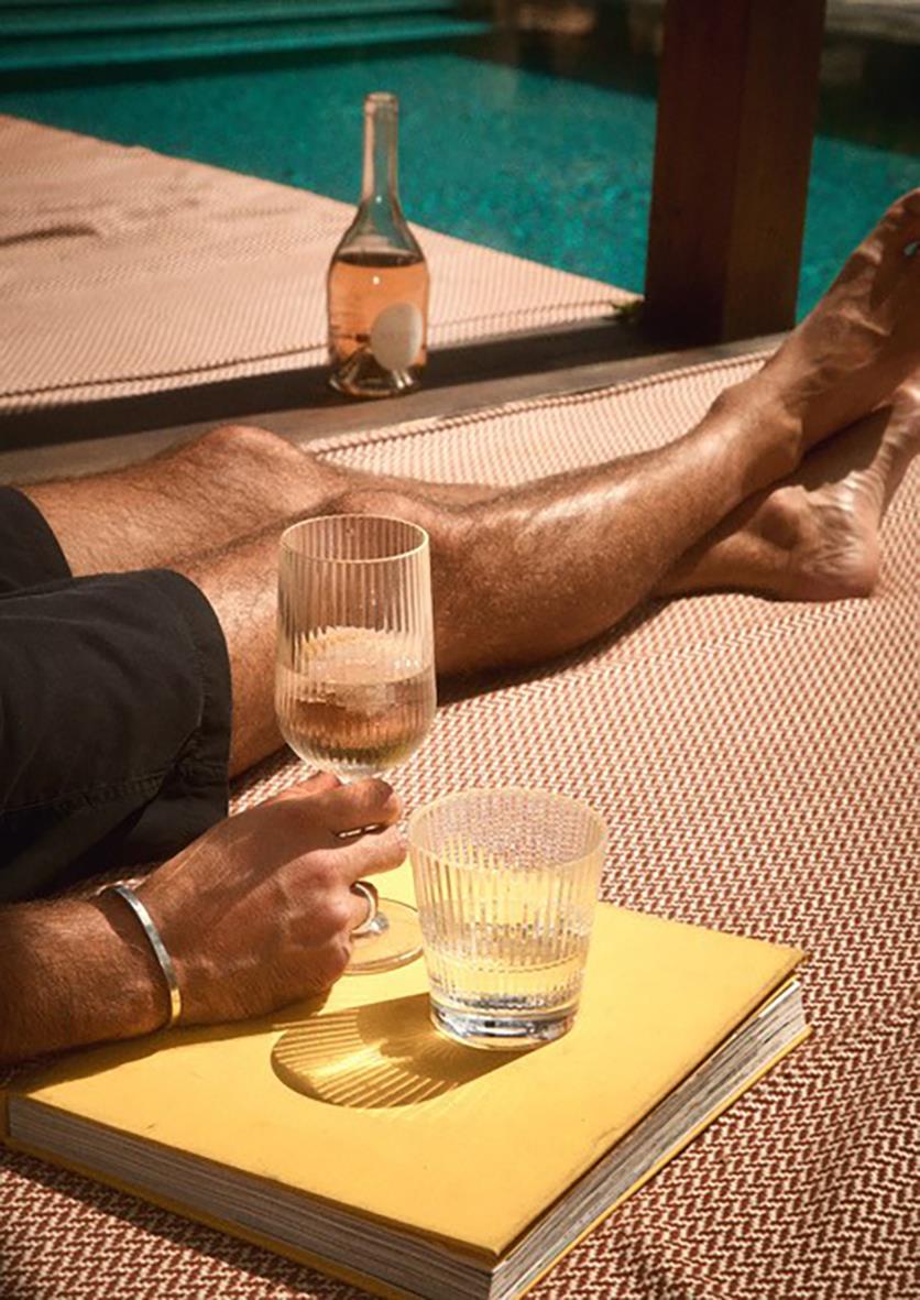 Person som vilar vid poolen med vinglas och ett gult anteckningsblock