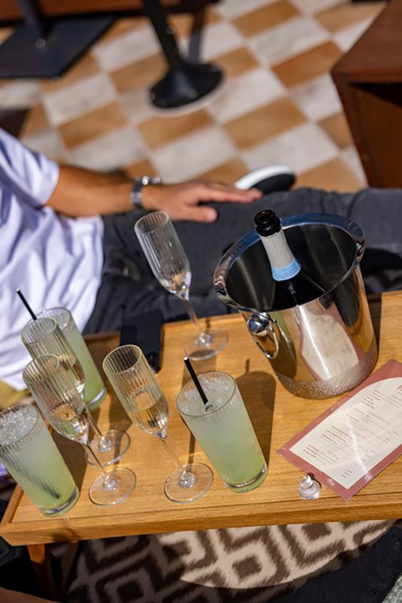 Champagneglas och drinkar på träbord med isvatten och en vinflaska i en isklubba
