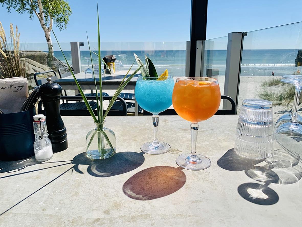 Två färgglada drinkar i Palma polykarbonatglas på bord med havsutsikt