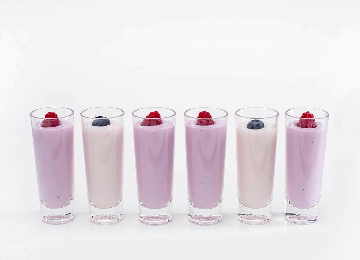 Sex shotglas av polykarbonat med olika färgade drycker och bär på toppen