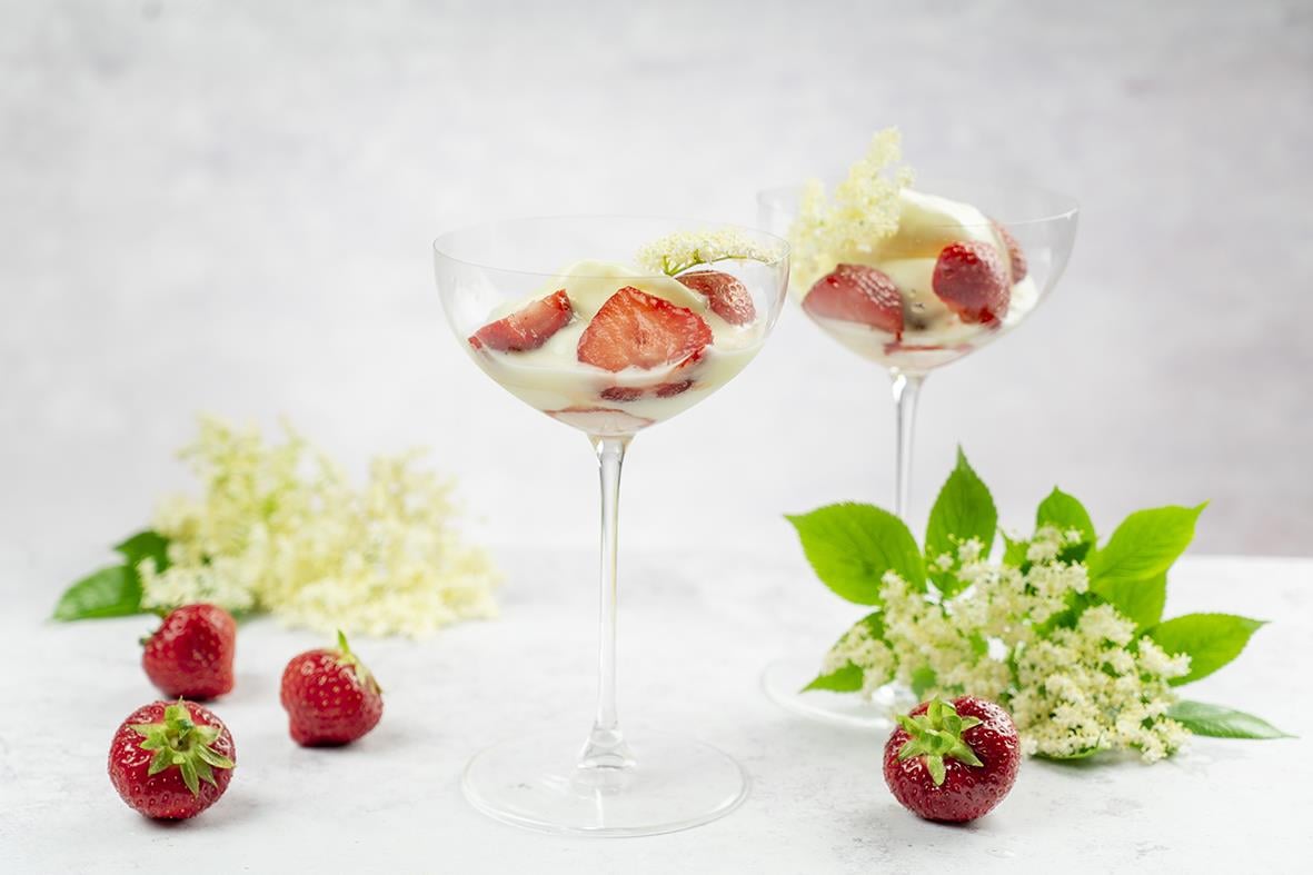 Två cocktailglas med jordgubbar och grönska på en ljus bakgrund