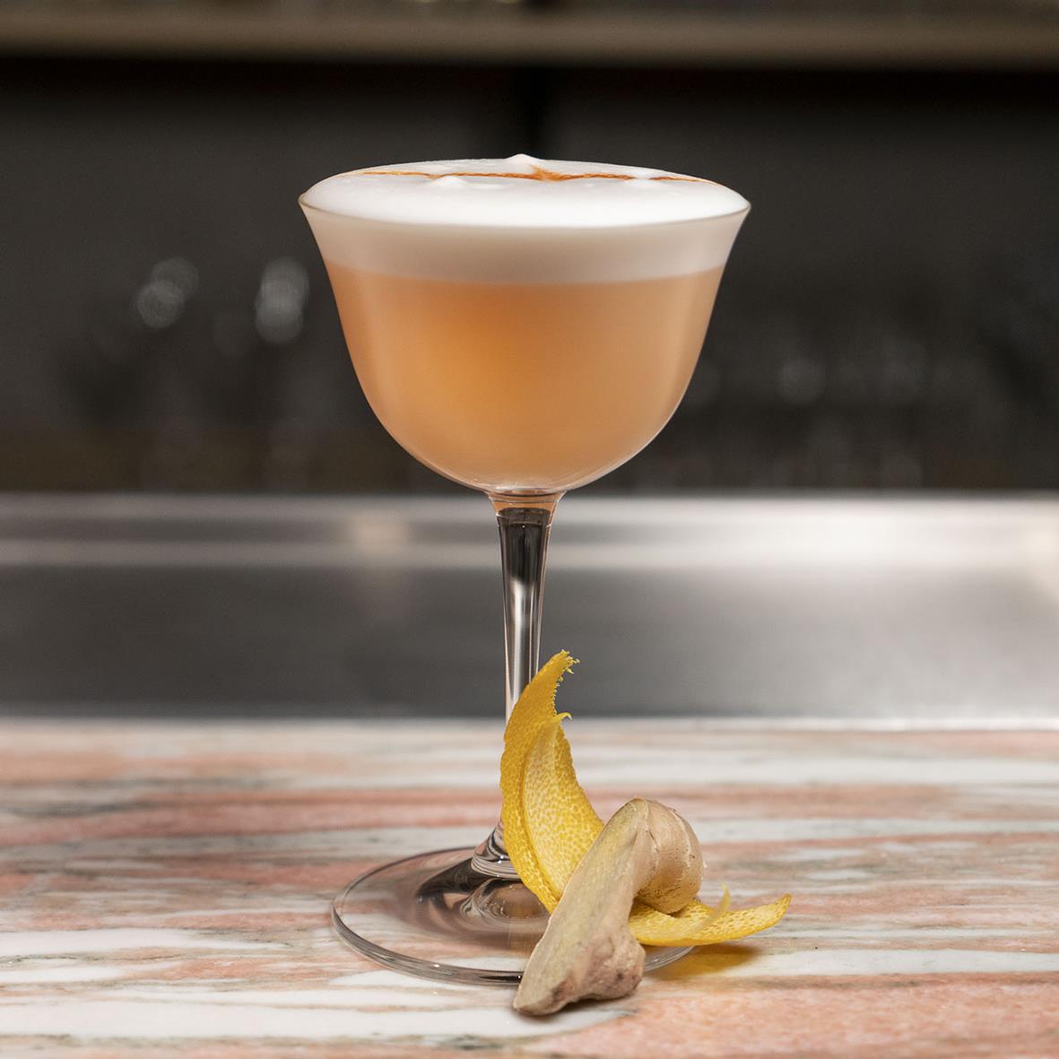 Cocktail i Riedel glas med citron- och ingefärsdekoration på träbord