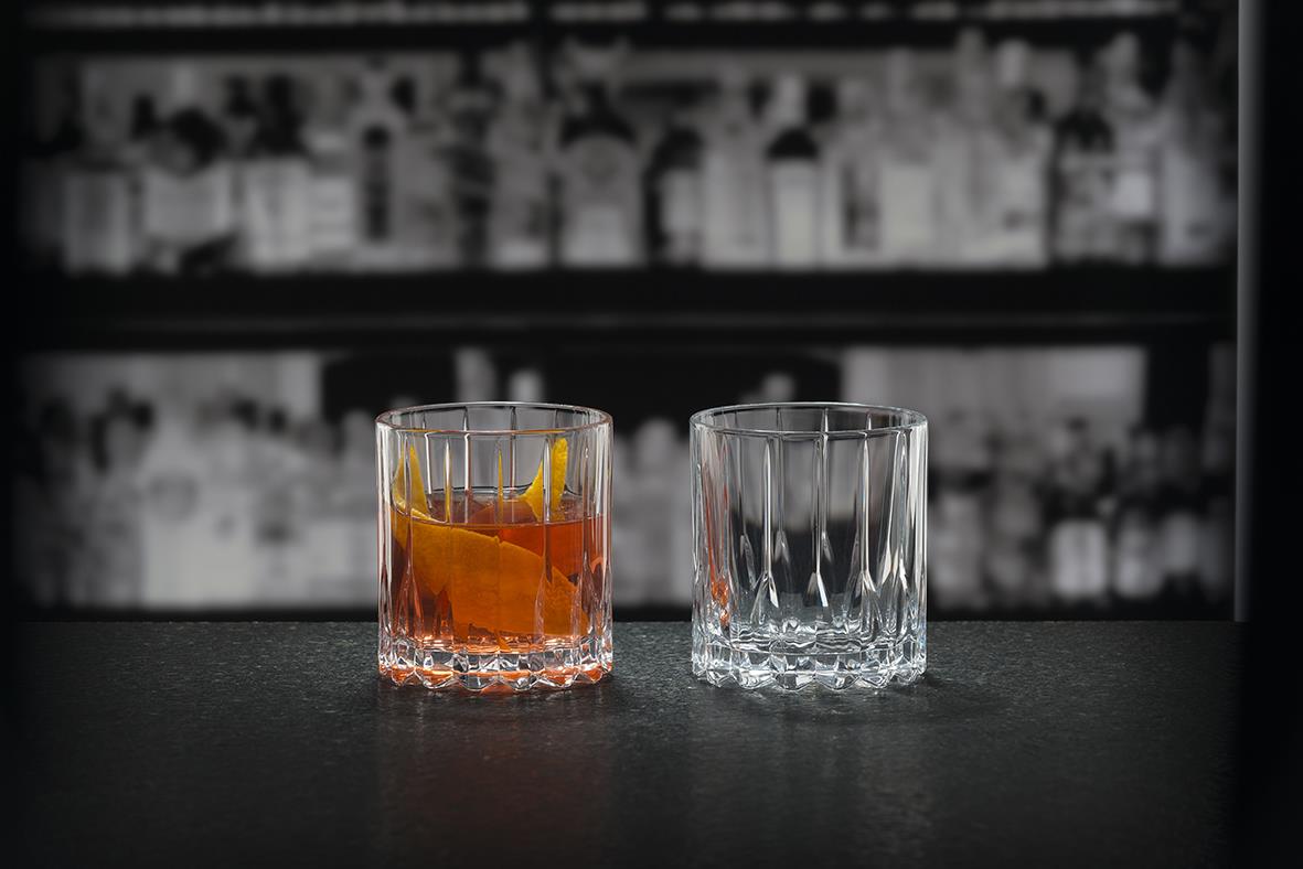 Två drinkglas, ett med orange dryck, på barhylla