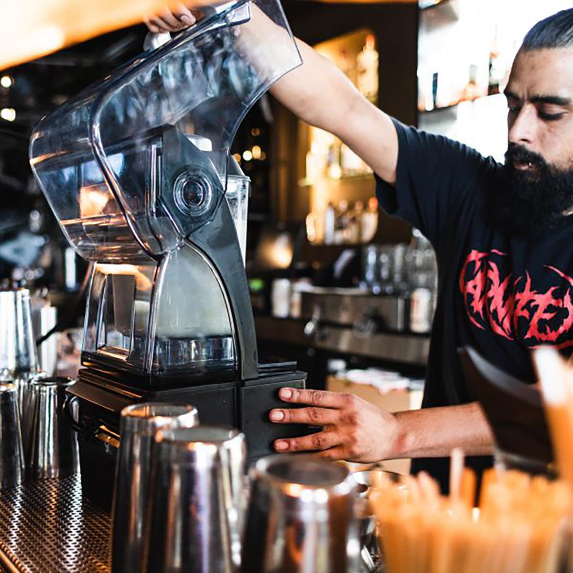 Person som använder en Vitamix The Quiet One-blender i ett kök eller barmiljö