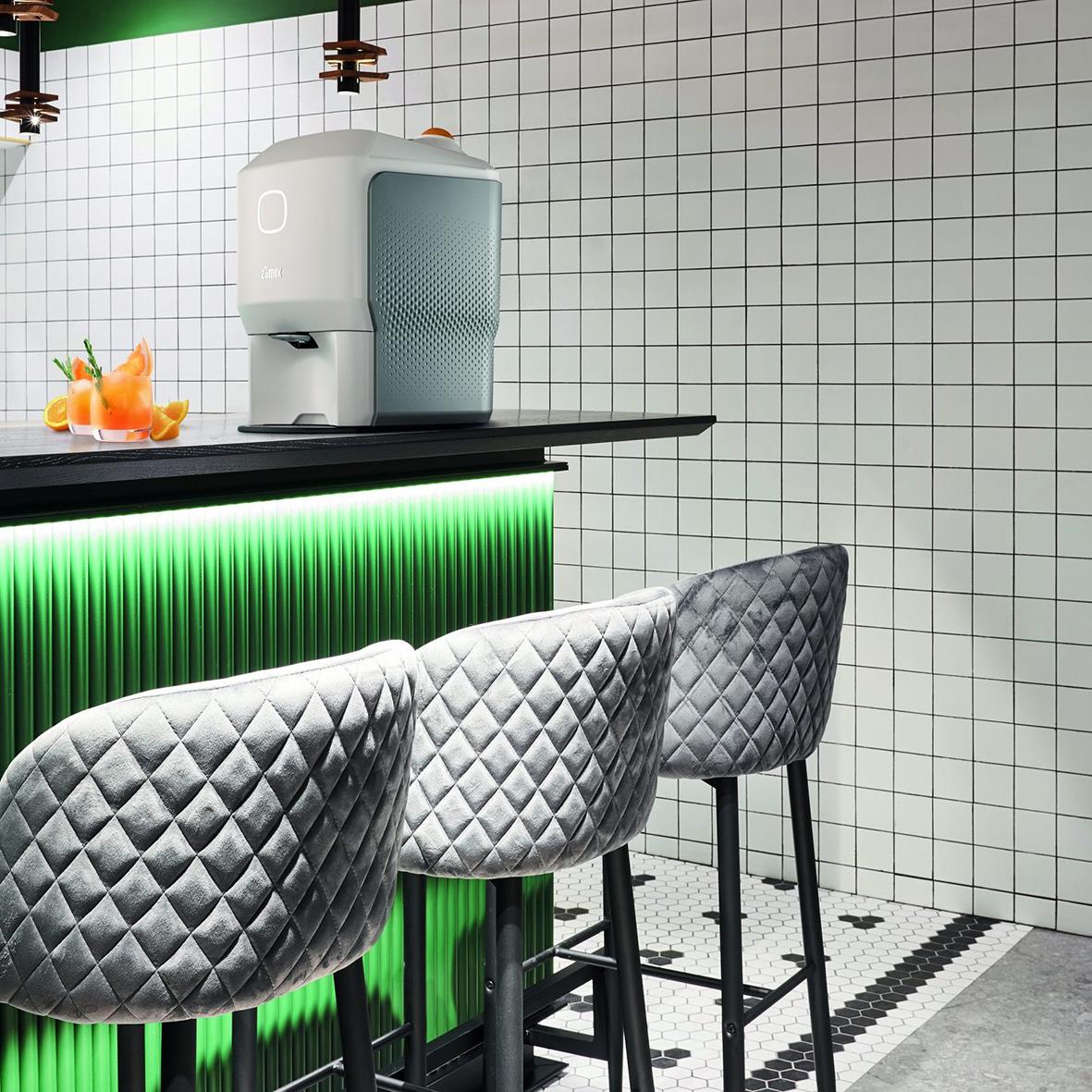 Juicepress Zumex Soul Series 2 automatisk svart/grå på bar med tre quiltade stolar
