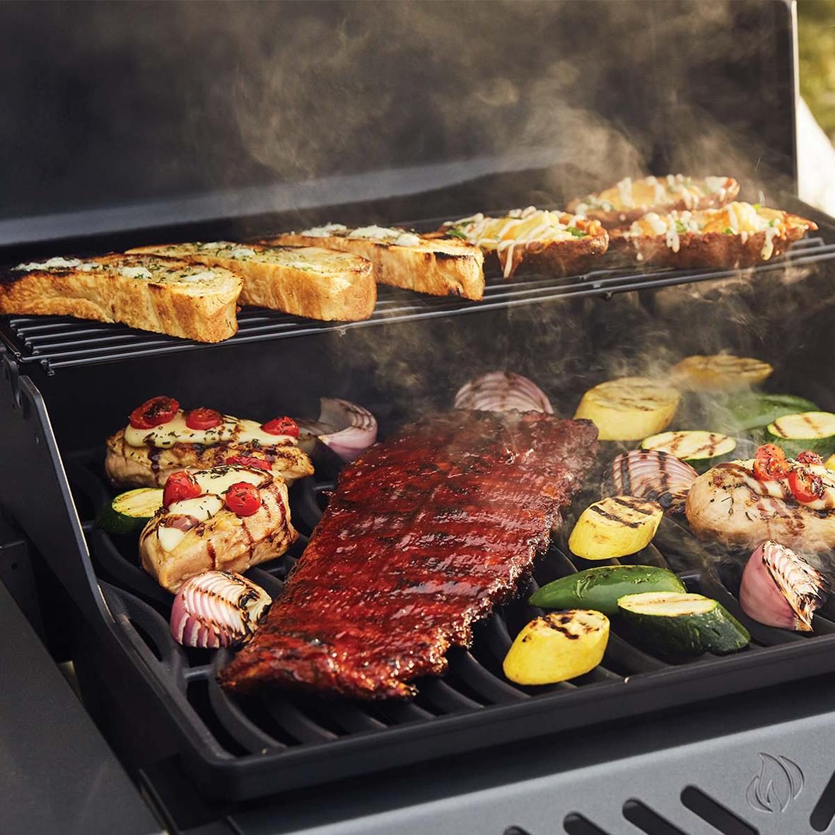 Gasolgrill Napoleon Freestyle 365 med kött, grönsaker och bröd som grillas