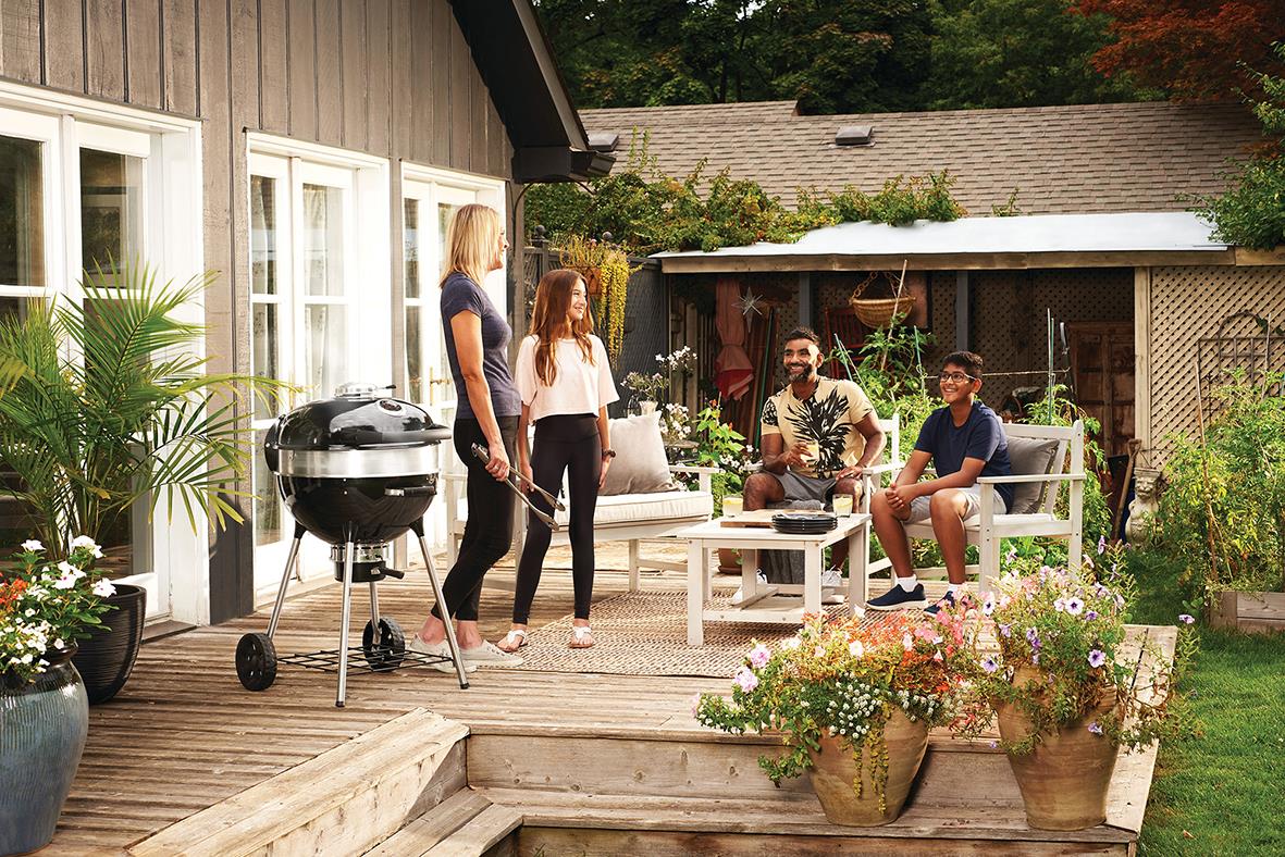 Grillning på uteplats med tre personer, kolgrill och trädgårdsdekorationer