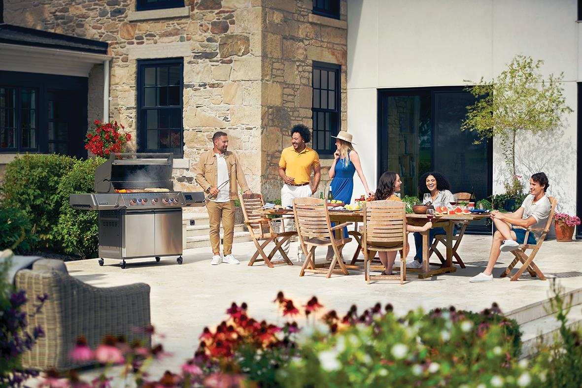 Grillfest utomhus med gasolgrill Napoleon Prestige 665 och sällskap vid bord