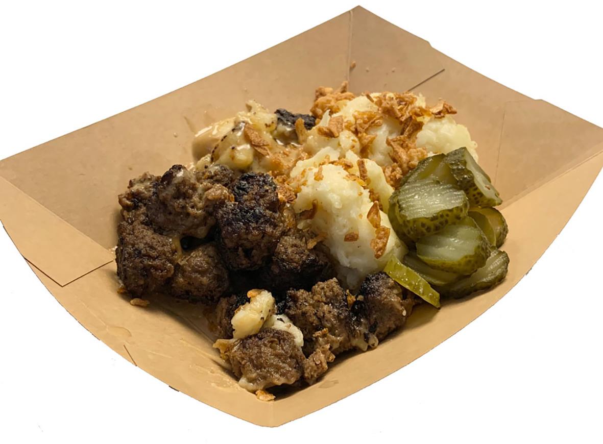 Friterad mat med mörk och ljus köttbit, potatis och inlagda gurkor på ett papper