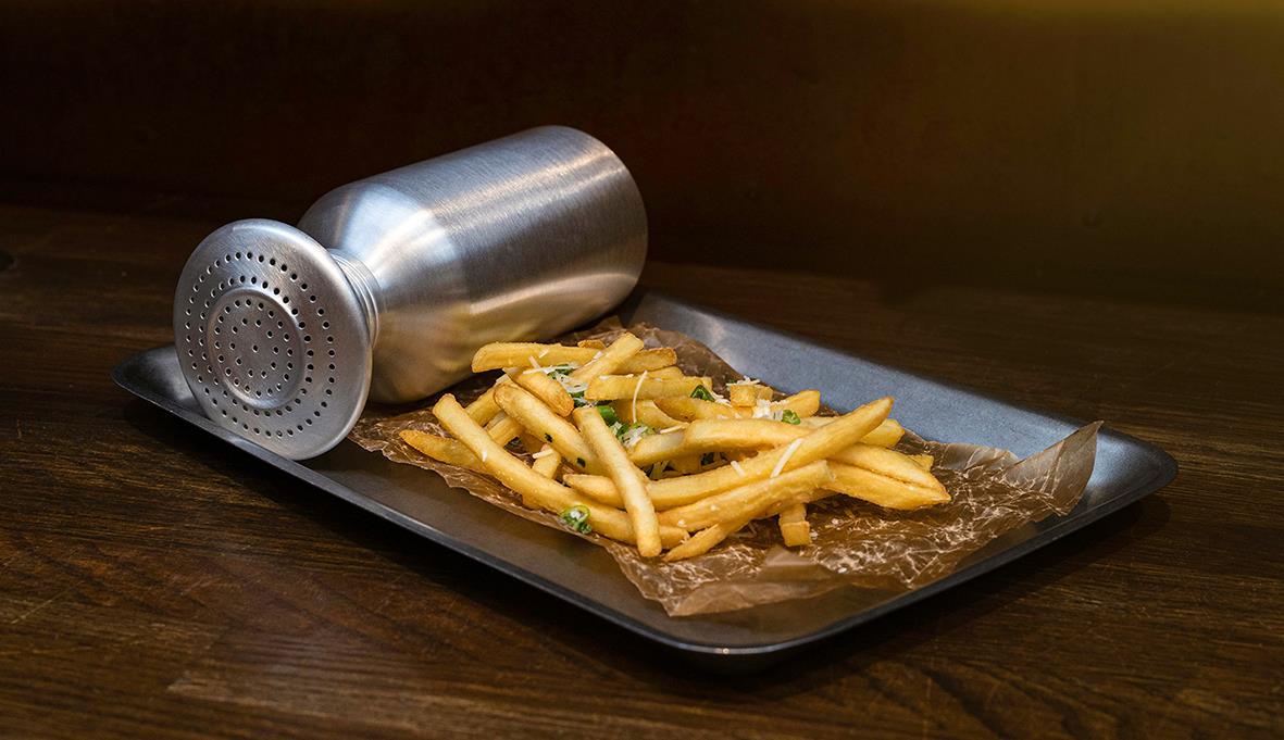 Rostfri serveringsbricka med pommes frites på träbord