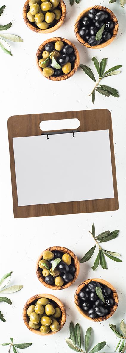 Oliver i små träskålar och en menyhållare av trä med handtag på en vit bakgrund